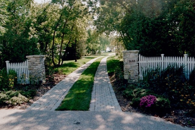 After stone driveway and stone wall with address number.