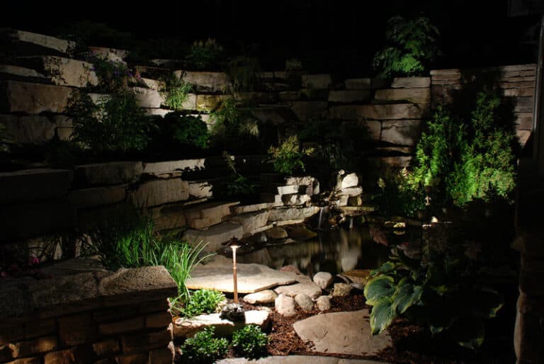 Outdoor lighting, displaying stone wall and plants.