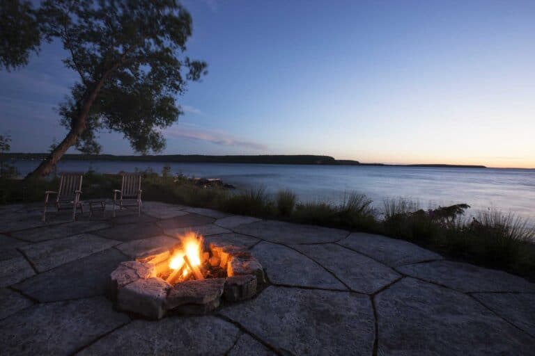Stone fireplace with a view of a body of water.