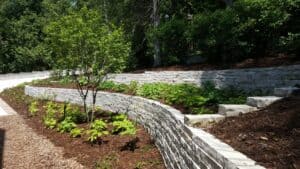 Stone wall with greenery and wood chips.