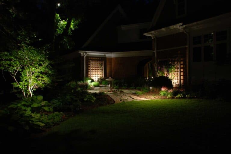 Outdoor lighting outside of house showcasing stone walkway and greenery.