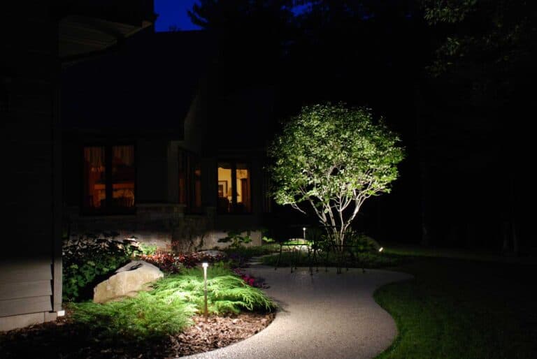 Outdoor lighting brightening walkway to house and landscaping.