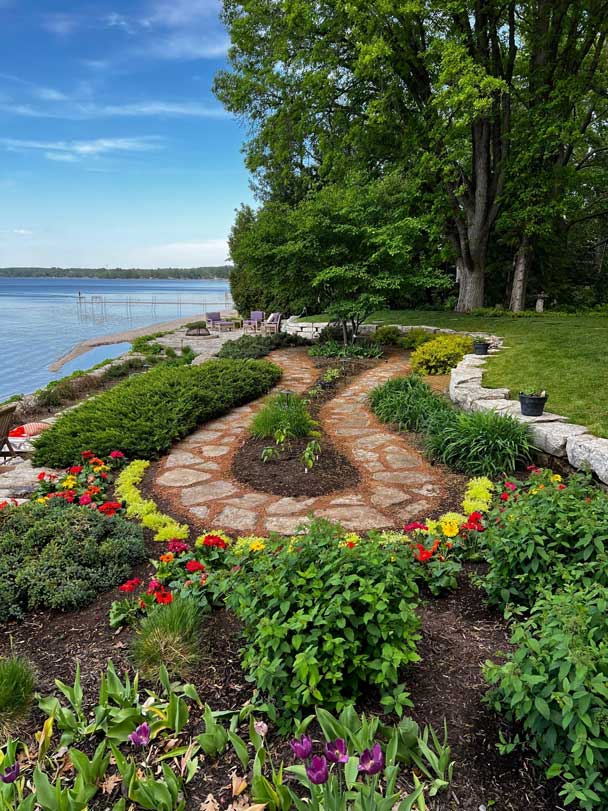 Stone walkway surrounded by greenery and colorful flowers.
